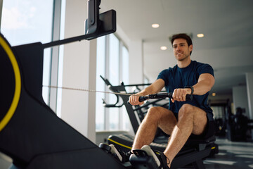Fototapeta premium Close up of athlete working out on rowing machine in health club.