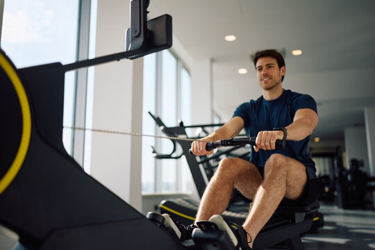 Close up of athlete working out on rowing machine in health club.