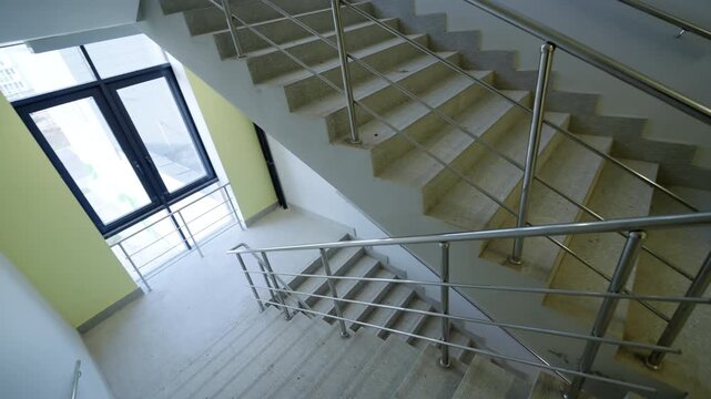 Modern public building features newly constructed concrete steps and safety metal railings. Bright daytime light creates fresh clean look