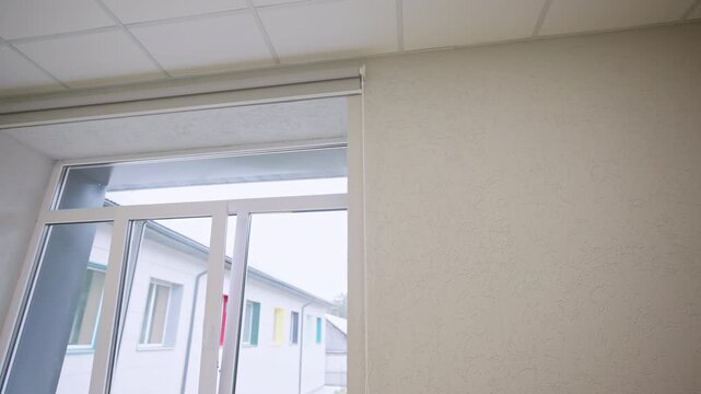 Textured plaster walls frame scenic outdoor view of houses near pine forest. Quiet school room looks spacious and freshly renovated