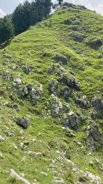 Vertical nature footage captured at Malsa, Abbottabad, Pakistan, showcasing rugged mountain cliffs, lush green hills, dramatic white clouds, and a breathtaking blue sky. Ideal for travel videos, 
