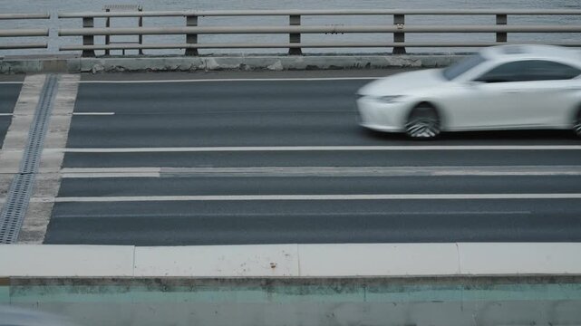 Speeding cars driving on riverside road with motion blur.
