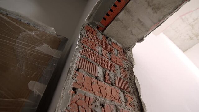 Basic construction materials stand near deep doorway under heavy concrete ceiling. Dusty indoor environment looks ready for active repair