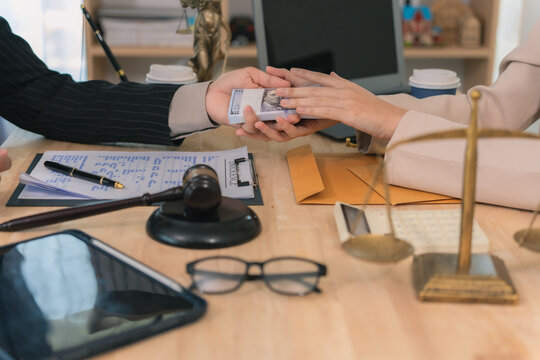 Woman hand giving bundle of money to lawyer or officer. Concept of bribery, corruption, and illegal payment in legal office. Client offering cash for lawsuit settlement or hidden financial crime.
