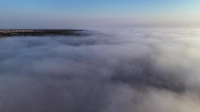 Dense fog covers Palanga landscape under colorful sunset sky.