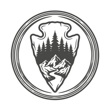 Circular badge with arrowhead mountain and forest landscape.