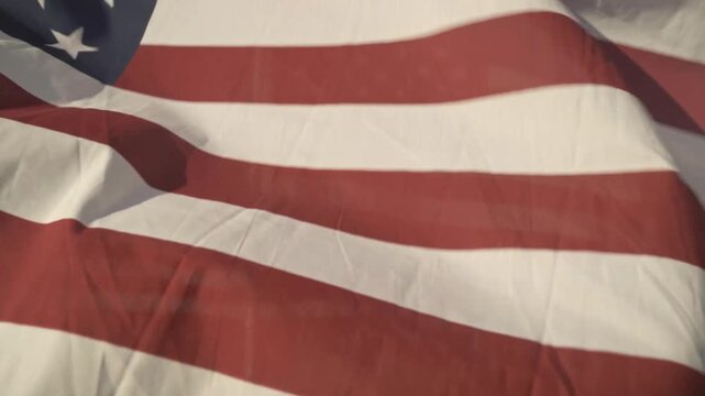 A close up, artistic shot of an American flag waving in the wind. The detailed texture of the red, white, and blue fabric creates a moving, patriotic display of national pride and honor.