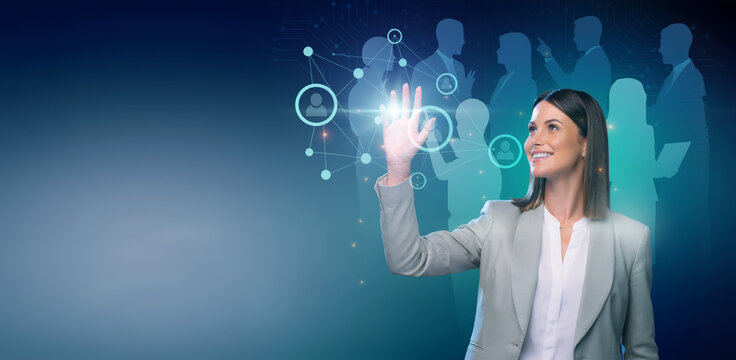 Confident businesswoman touches a glowing digital interface surrounded by network icons and silhouetted colleagues symbolizing corporate innovation.
