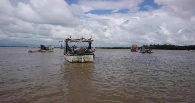 Pelicans on a fishing vessel off the shallow, muddy coast of Orange Valley fishing village in the Gulf of Paria with the mountains of Port-of-Spain and Venezuela visible in the background