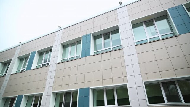 Modern multi-story building features clean tiled facade and plastic windows. Fresh architectural design creates bright atmosphere