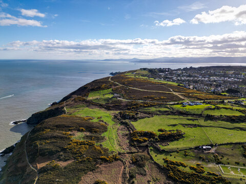 Aerial view of Howth cliffs and coastal landscape with green fields, gorse bushes, and residential areas overlooking the Irish Sea in Dublin, County Dublin, Ireland.