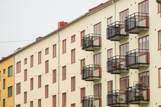Apartment building facade with balconies on cloudy day.