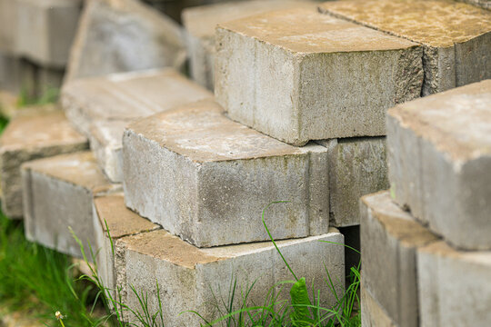 Close view of weathered concrete pavers and grass.