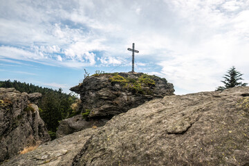 Fototapeta premium Summit cross on the Rauchröhren rock formation along Kaitersberg ridge in the Bavarian Forest, Germany.