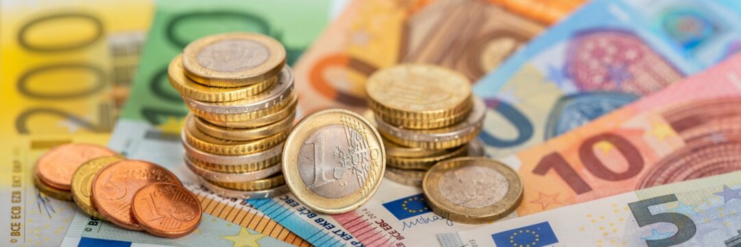 Viele Euro Banknoten und M&uuml;nzen liegen auf einem Haufen zusammen