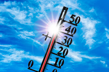 Auf einem Thermometer zeigt die Skala sehr hohe Temperatur um 40 Grad Celsius vor blauem Himmel mit strahlender Sonne - FOTOMONTAGE