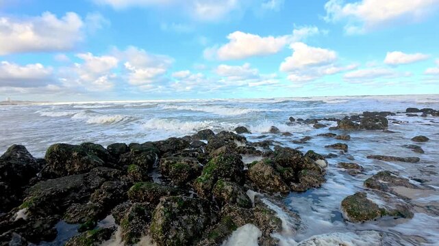 Powerful ocean waves crashing onto a rocky coastline under a dramatic cloudy sky.