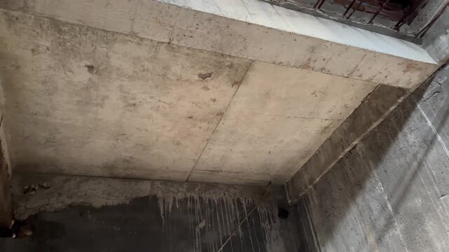 Unfinished raw concrete ceiling and beam support structure inside building