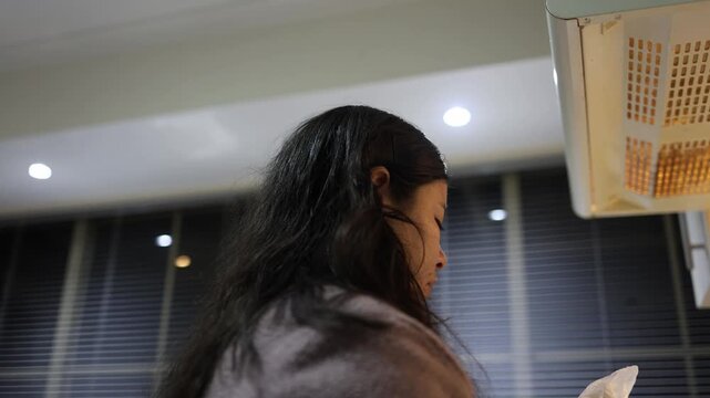 A Latina girl poses thoughtfully in a modern kitchen at night, illuminated by soft overhead lighting, with blinds in the background. The close-up and medium shots capture her focused mood