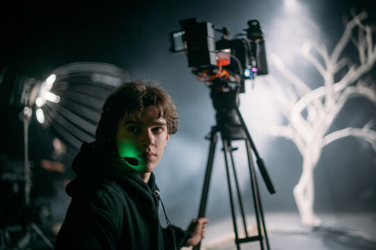 The director of photography holds a camera in his hands on the set in the pavilion. A professional videographer films a movie, commercial or TV series in a studio.