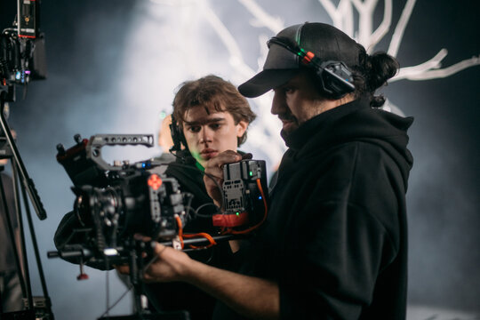The director of photography holds a camera in his hands on the set in the pavilion. A professional videographer films a movie, commercial or TV series in a studio.