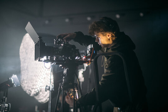 The director of photography holds a camera in his hands on the set in the pavilion. A professional videographer films a movie, commercial or TV series in a studio.