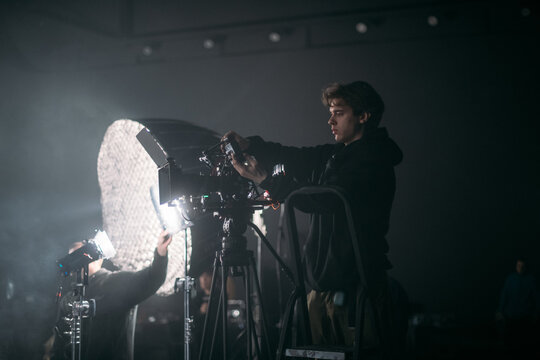 The director of photography holds a camera in his hands on the set in the pavilion. A professional videographer films a movie, commercial or TV series in a studio.