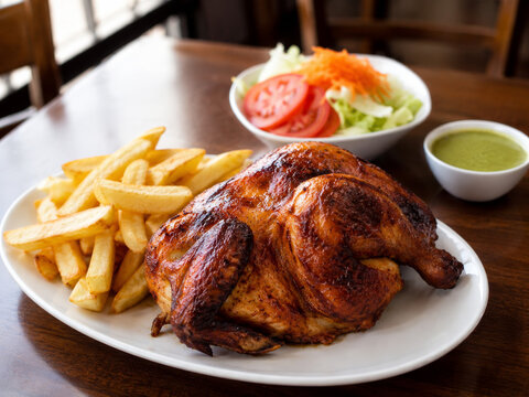  Pollo a la Brasa peruano servido con papas fritas, ensalada fresca y salsa cremosa de aj&iacute; verde.