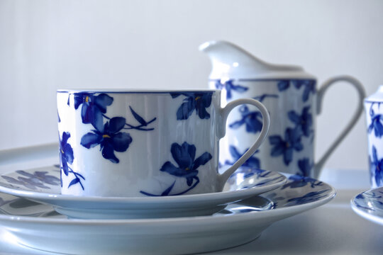 White porcelain tea set featuring a delicate blue floral pattern on cups, saucers and pitcher