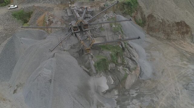 Aerial drone orbit shot of an industrial stone crushing plant operating at a mining site.