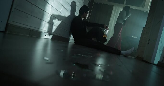 Depressed man sit floor drink bottle alcohol, angry woman scream. Domestic conflict, relationship crisis. Alco addiction concept. Couple arguing dark room home. Quarrel people separation bad break up.