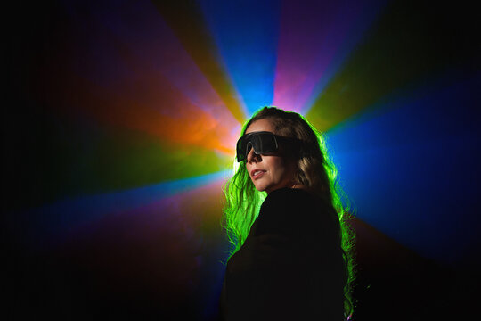  Portrait of fashion young girl in cool sunglasses in red and blue neon light in the studio