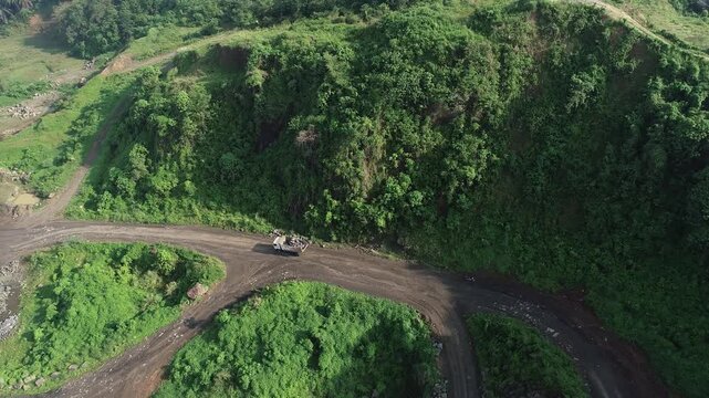 Aerial drone view of a dump truck transporting material on a dirt road at an industrial mining site.