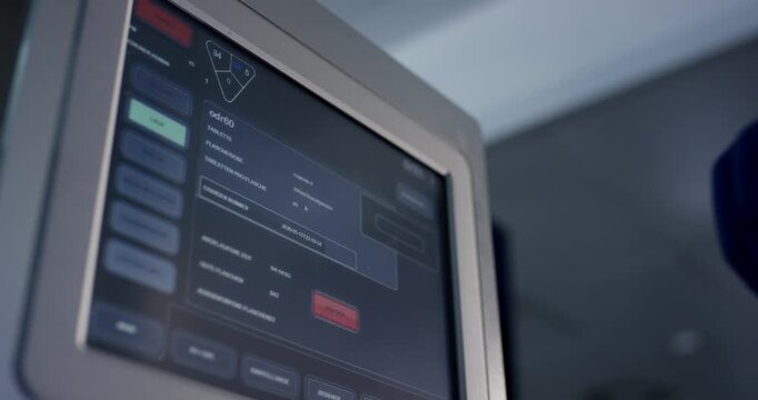 Close up of gloved hand operating digital touchscreen control panel interface in clean industrial facility