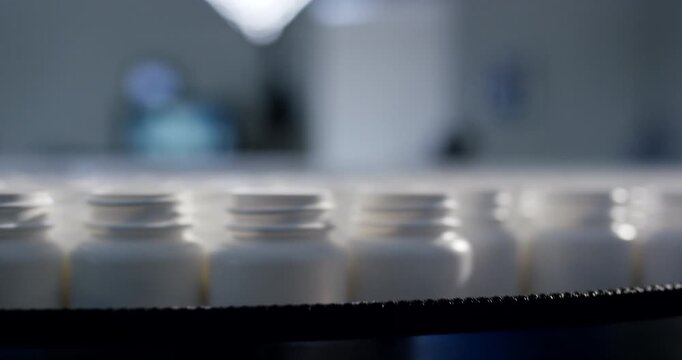 Extreme close up tracking shot of rows of empty open white plastic bottles on automated conveyor belt