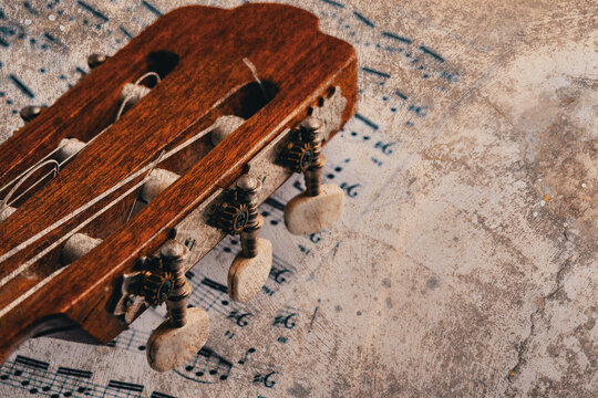  Cabezal de guitarra de madera vintage sobre suelo arenoso texturizado; concepto de m&uacute;sica antigua e instrumento retro para dise&ntilde;o editorial musical. Cabezal de guitarra de madera antigua sobre suelo 