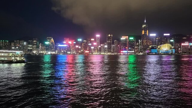 A sweeping night view of Hong Kong's iconic skyline and the vibrant urban landscape set against the dark waters of Victoria Harbour