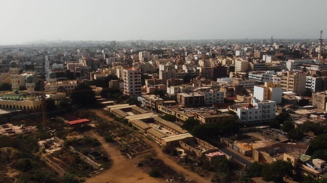 Drone flies past Dakar mosque with green dome alongside dense urban skyline