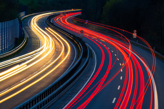 Autobahn A46 at evening twilight in Iserlohn (Sauerland, Germany) from a bridge, long time exposure with bent light traces of passing car lights in motion. Double S-curve