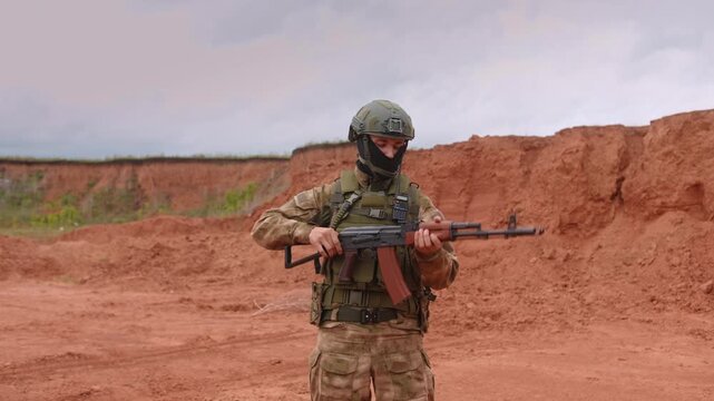 Soldier aiming and moving with rifle across desert training landscape with red rock formations, helmet, tactical gear, and overcast light in rugged outdoor military setting