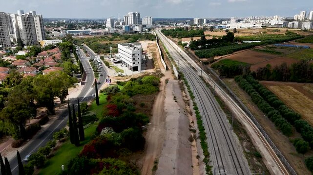 Forward Flying Cinematic Drone Shot Along Railway Tracks on Western Border of Rehovot, Israel, Smooth Aerial Travel Footage Over Suburban Rail Corridor, Atmospheric Transport Scene