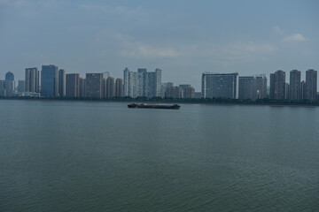 A cargo boat sailing on the Qiantang River with modern city skyline background in Hangzhou © 家俊 周
