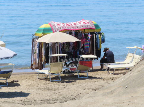 Beach trader selling clothes to a local tourist at Marina di Latina, Italy
