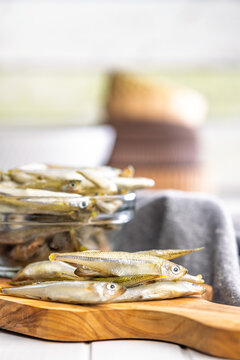 Fresh Whitebait Small Fish Stack on Wooden Board With Glass Bowl of Seafood