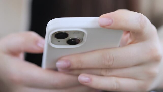 Close-up of hands holding smartphone. Fingers tap screen, showing engagement. Person focused, intent on device. Ideal for tech, communication, or social media themes. Suitable for apps, mobile usage