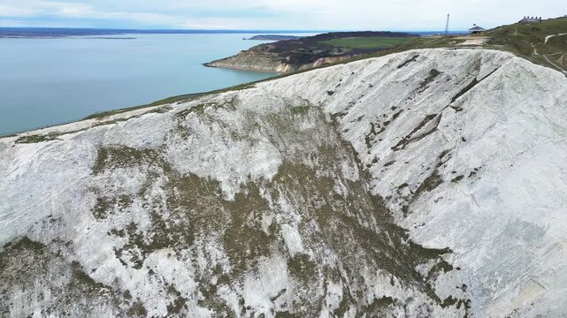 4K panning drone footage following the chalk cliffs of Satchells Bay to the headland and coastguard station on the Isle of Wight in clear summer weather.