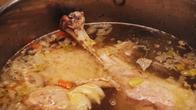 Turkey legs are simmering in a rich broth with vegetables. The soup gently boils. Slow cooking makes the meat tender and juicy while creating a clear, hearty broth. . High quality 4k footage