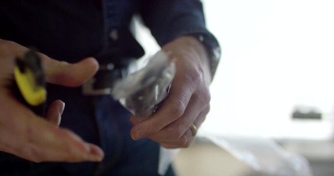 Close up of a man connecting a measuring probe cable to a black power plug in a wall socket
