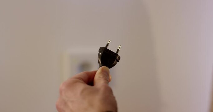 Close up of a man checking a wall power outlet with a multimeter probe as a green light turns on