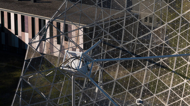 Aerial view of the Westerbork Synthesis Radio Telescope, showing the intricate metal lattice structure of the dish and receiver assembly in Zwiggelte, Drenthe, Netherlands.
